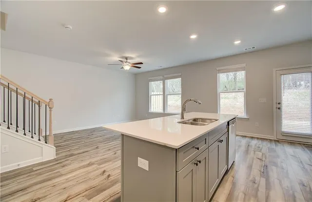 a kitchen that has a sink a window and wooden floor