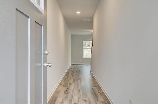 a view of a hallway with wooden floor and a bathroom