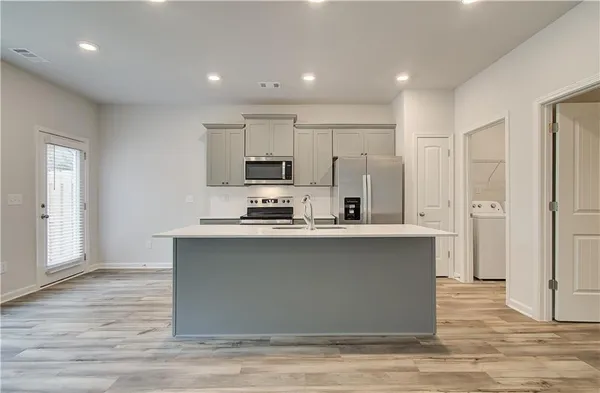 a kitchen with stainless steel appliances granite countertop a stove top oven a sink and a refrigerator