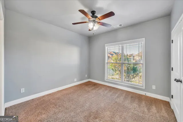 an empty room with windows and ceiling fan