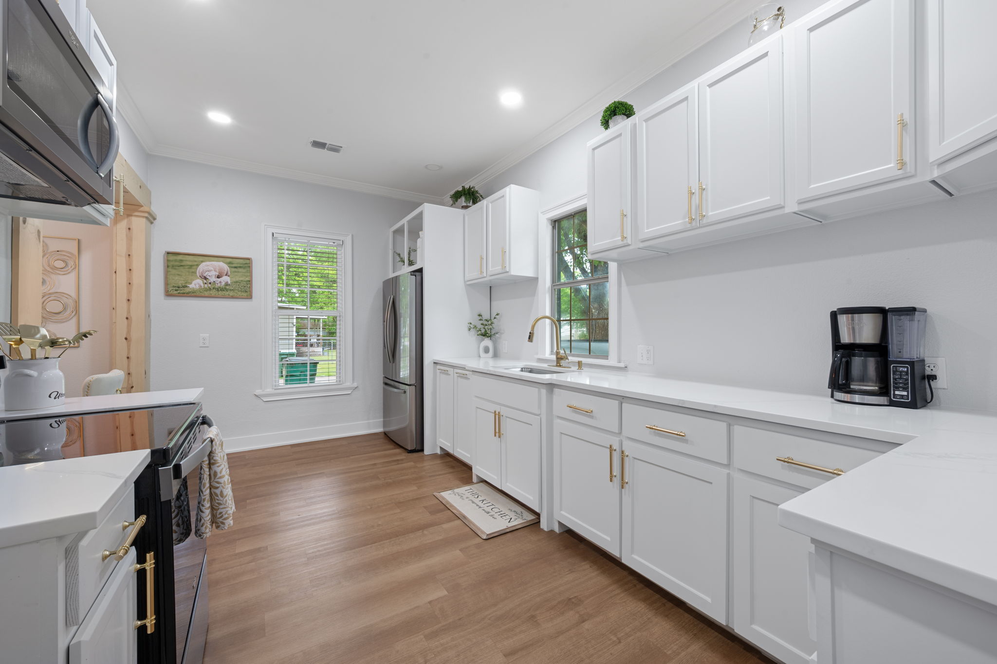 602 East 6th Street Cameron, TX 76520 - Photo 16 of 40 Kitchen featuring white cabinetry with gold-finish hardware, light-toned countertops, and wood-finish flooring