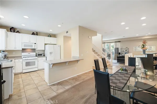 a kitchen with stainless steel appliances kitchen island granite countertop a stove a refrigerator a kitchen island a table and chairs