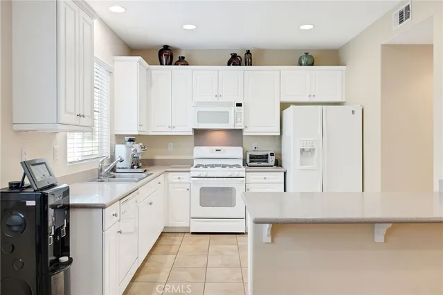 a kitchen with a sink a stove a refrigerator and white cabinets