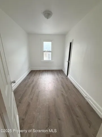 an empty room with wooden floor and window
