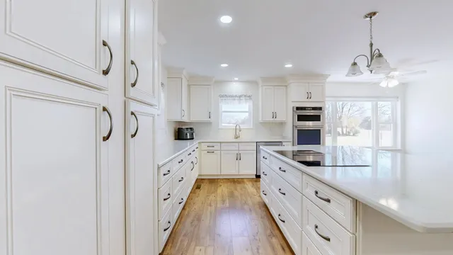 a large kitchen with granite countertop a stove top oven a sink dishwasher and a refrigerator with wooden floor