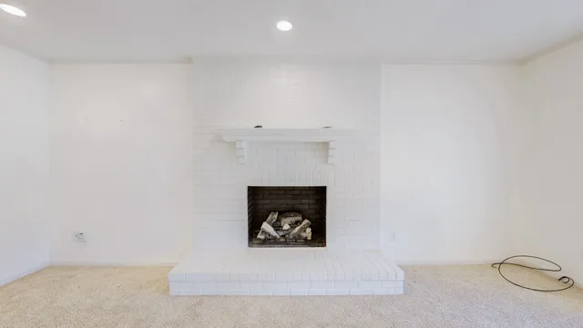 a view of an empty room with a window and fireplace