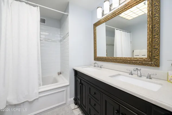 a bathroom with a double vanity sink mirror and a bathtub