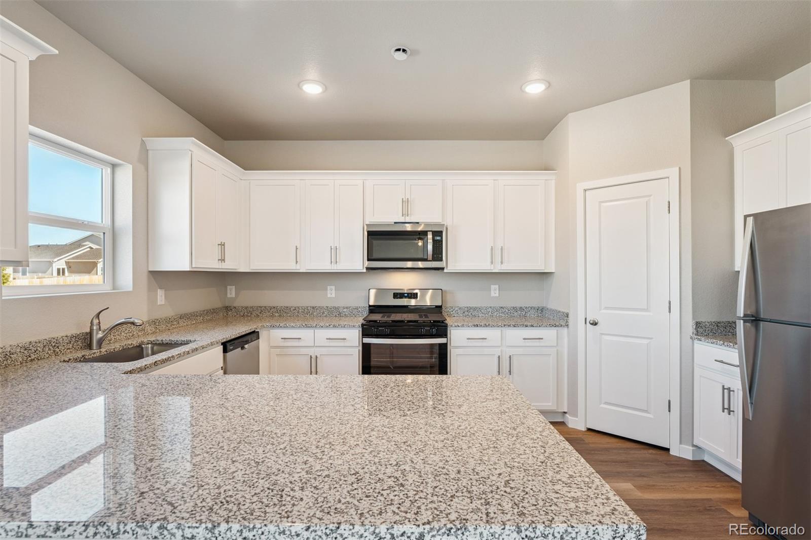 2181 Christina Street Fort Lupton, CO 80621 - Photo 3 of 39 a kitchen with granite countertop a refrigerator stove and sink