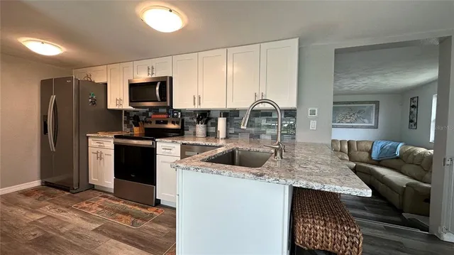 a kitchen with stainless steel appliances granite countertop a refrigerator a stove a sink a counter space and cabinets