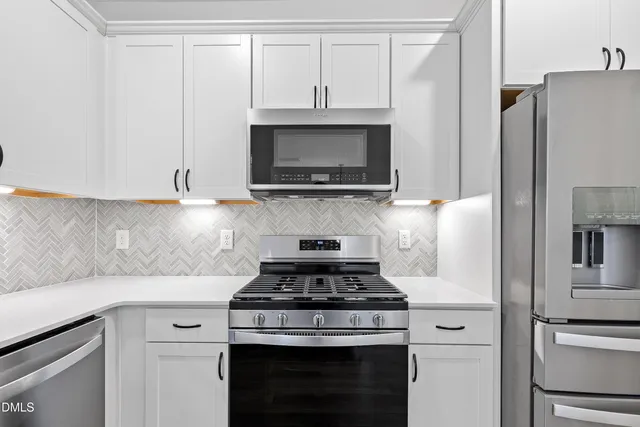 a kitchen with stainless steel appliances granite countertop a stove a refrigerator and a microwave