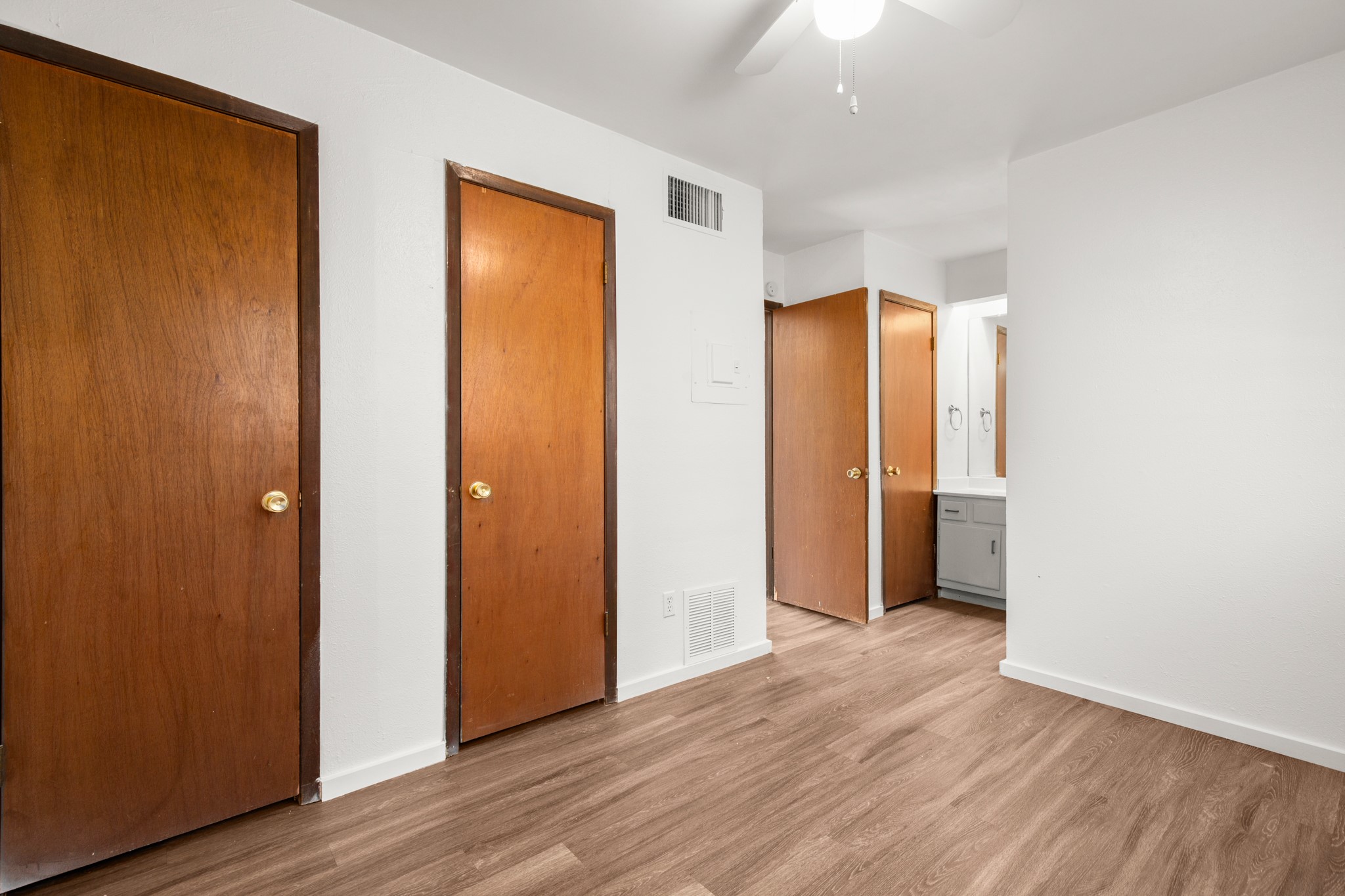 4205 Speedway, Unit 107 Austin, TX 78751 - Photo 12 of 15 Room featuring wood-finish flooring, white walls, and multiple solid wood doors with brass hardware