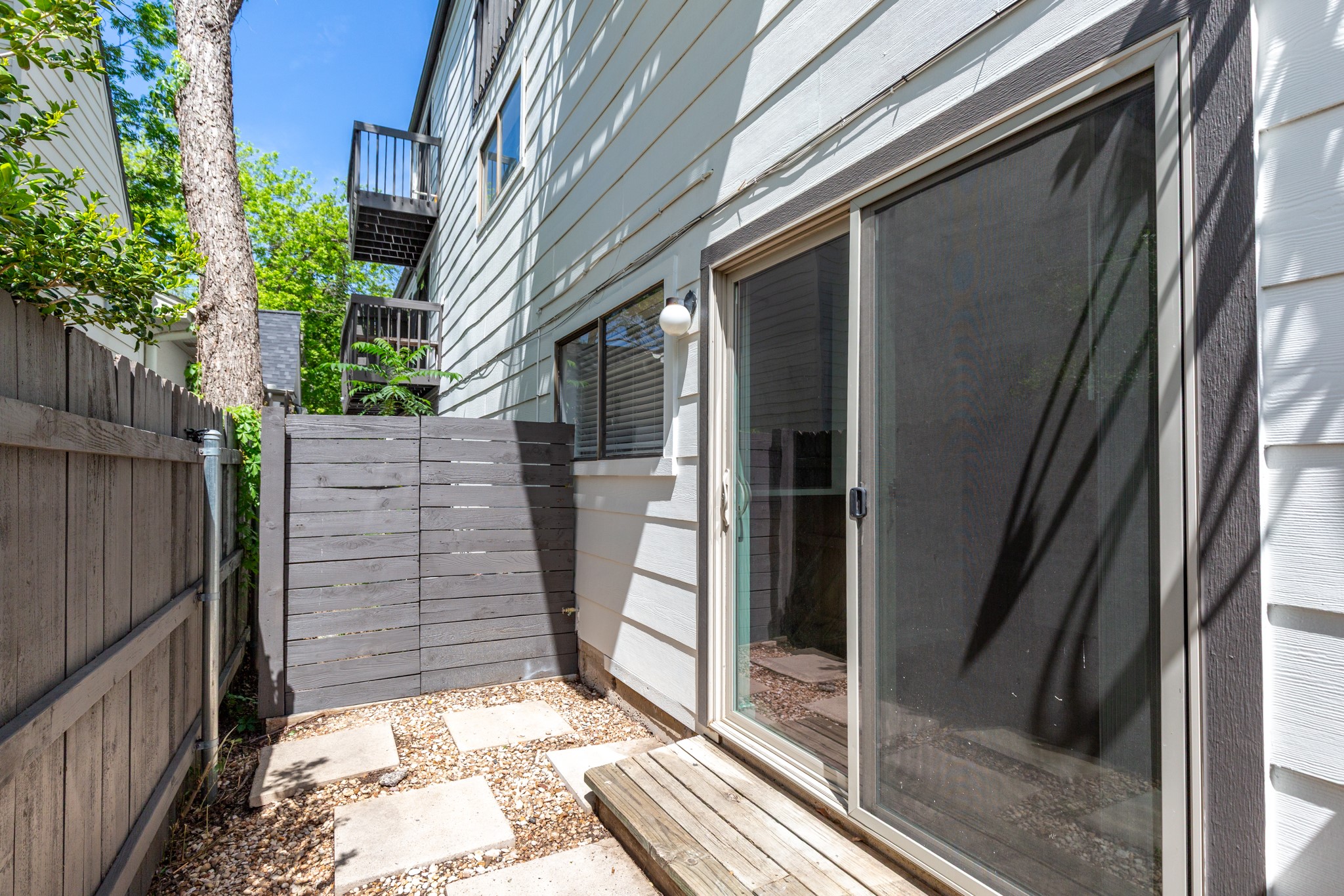 4205 Speedway, Unit 107 Austin, TX 78751 - Photo 2 of 15 Private outdoor patio featuring flagstone pavers, gravel ground cover, and a privacy fence
