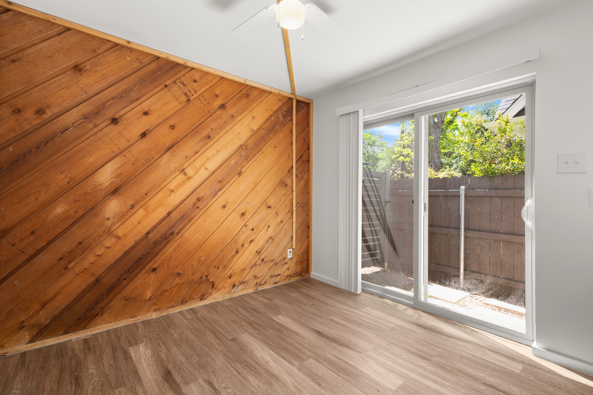 4205 Speedway, Unit 107 Austin, TX 78751 - Photo 4 of 15 Room featuring a diagonal wood plank accent wall, wood-finish flooring, and a ceiling fan
