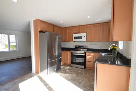 a kitchen with granite countertop a refrigerator and a stove top oven