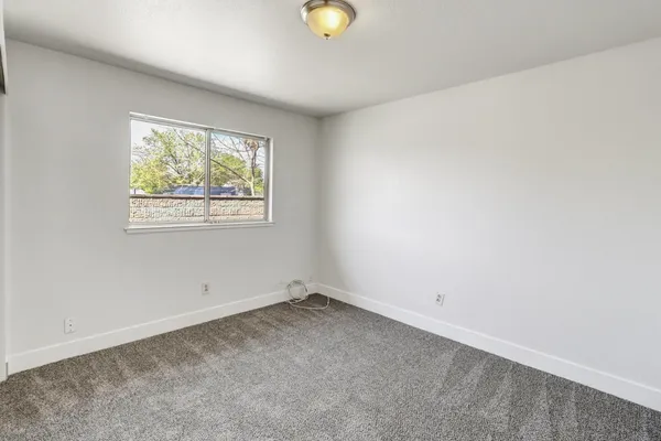 an empty room with window and plant