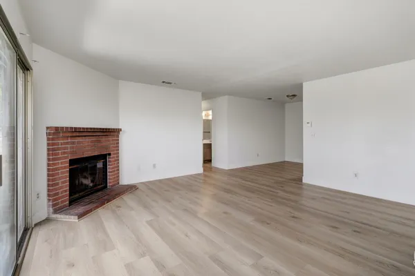 a view of empty room with wooden floor and fireplace
