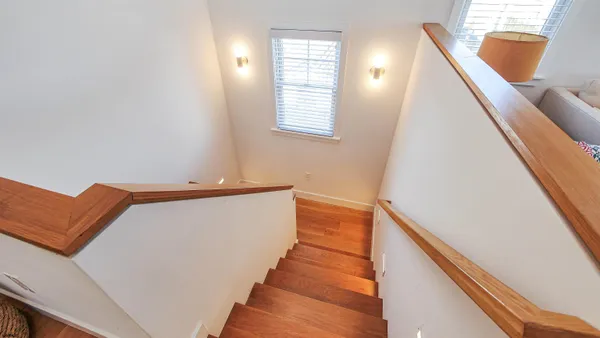 a view of a hallway with wooden floor and stairs