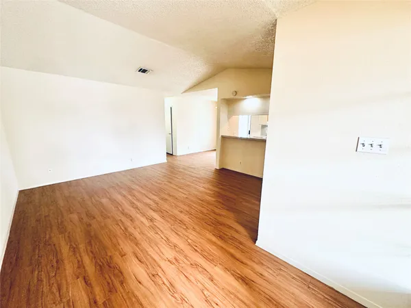 a view of an empty room with wooden floor