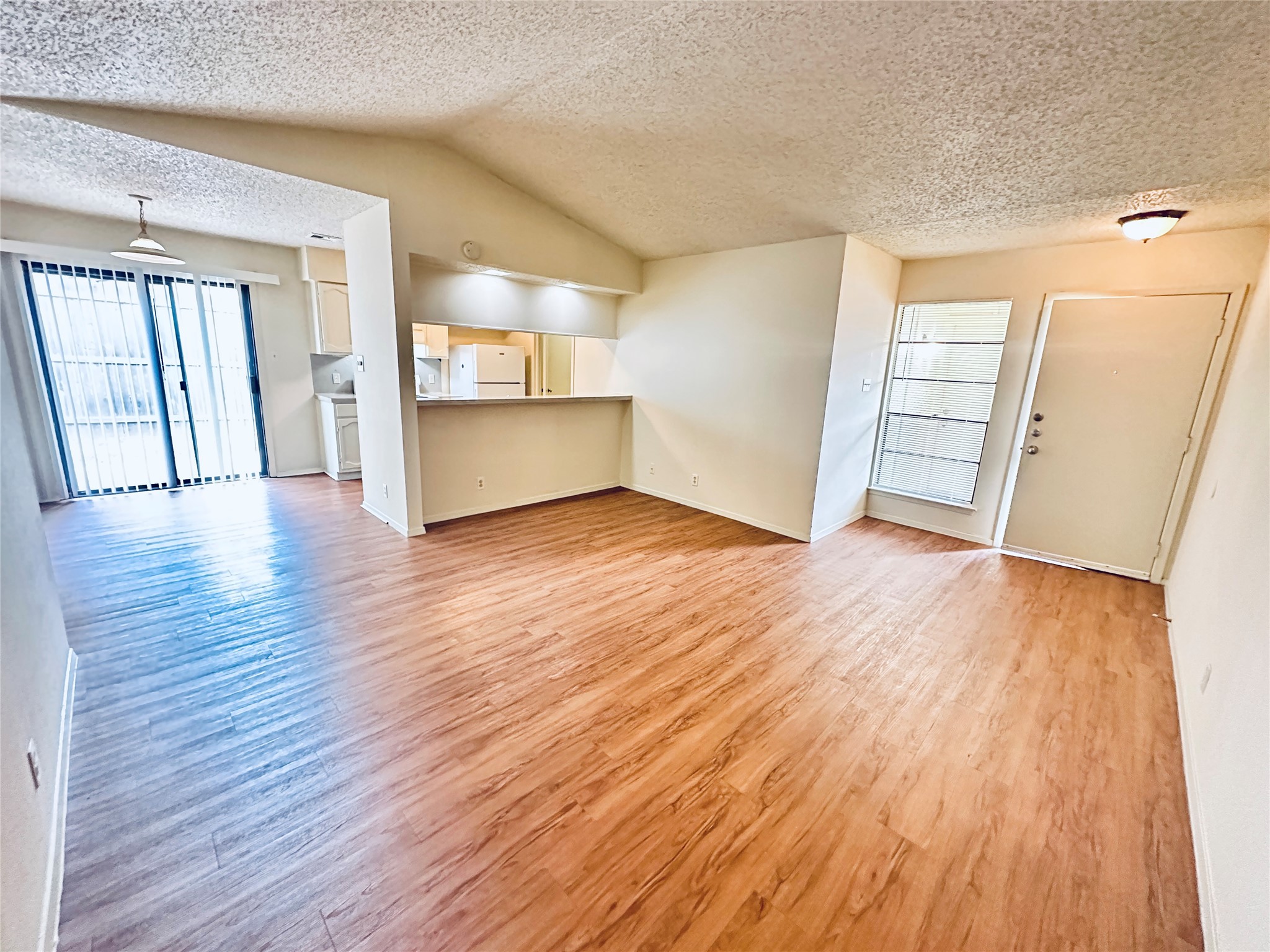12504 Tree Line Drive, Unit B Austin, TX 78729 - Photo 4 of 22 Unfurnished living room featuring light wood finished floors, a textured ceiling, and plenty of natural light