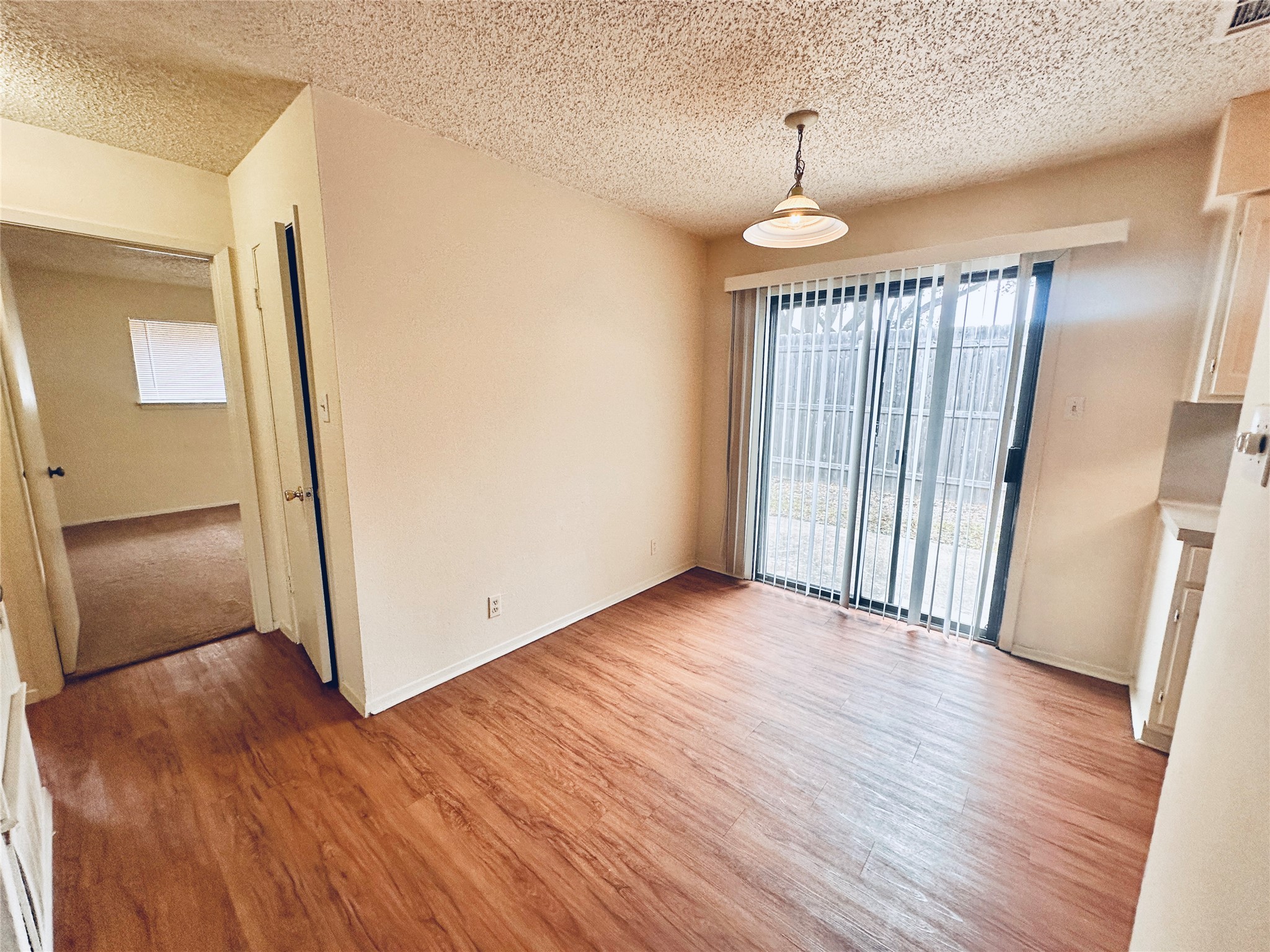 12504 Tree Line Drive, Unit B Austin, TX 78729 - Photo 7 of 22 Unfurnished dining area featuring light wood-type flooring and a textured ceiling