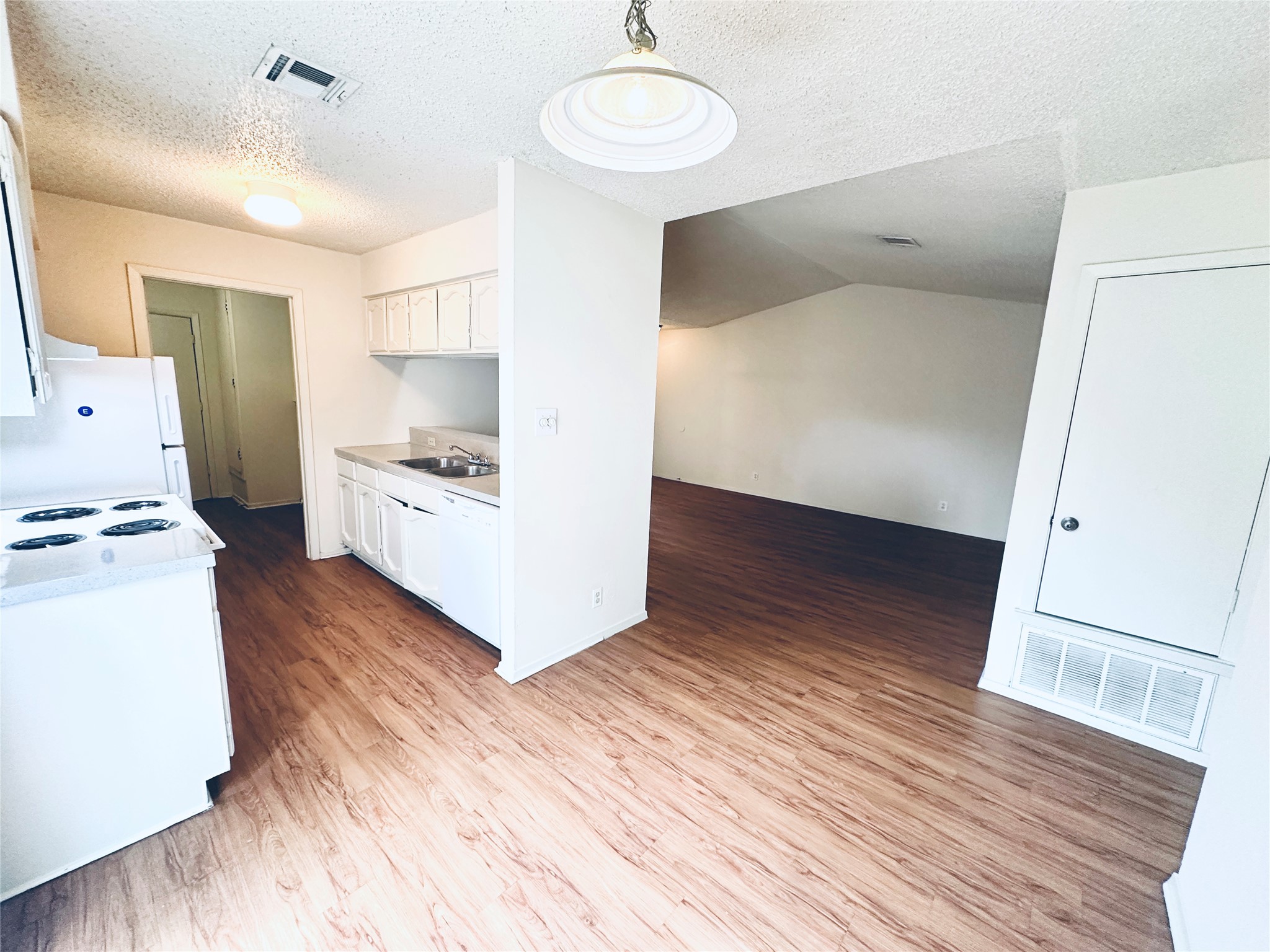 12504 Tree Line Drive, Unit B Austin, TX 78729 - Photo 22 of 22 Kitchen featuring light countertops, light wood finished floors, white cabinets, white appliances, and open floor plan