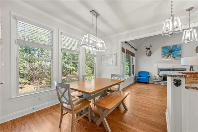 a dining room with wooden floor a chandelier a wooden table and chairs