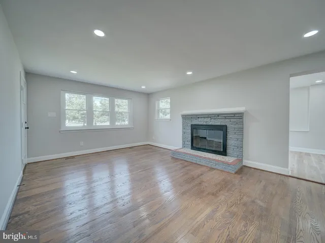 an empty room with wooden floor fireplace and windows