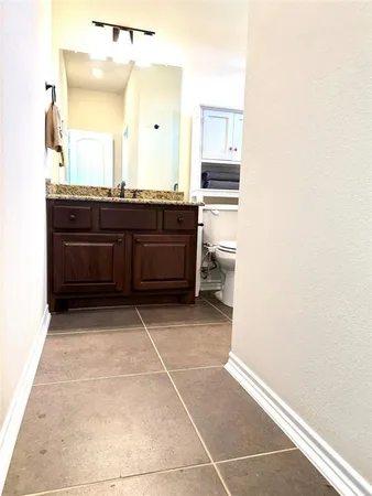 a bathroom with a granite countertop toilet sink and mirror
