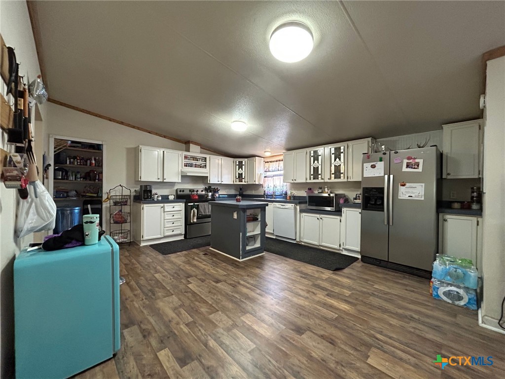 850 Blakely Road Gatesville, TX 76528 - Photo 23 of 32 a kitchen with stainless steel appliances kitchen island granite countertop a refrigerator a stove a sink dishwasher and white cabinets with wooden floor