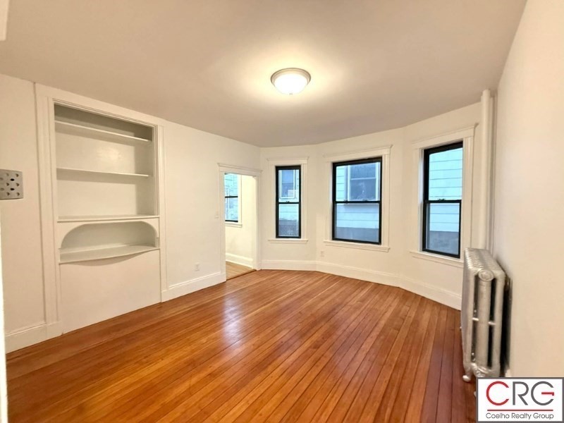 24 University Road, Unit 1 Brookline, MA 02446 - Photo 1 of 38 a view of an empty room with wooden floor and a window