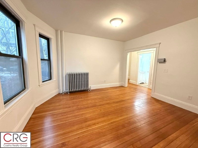24 University Road, Unit 1 Brookline, MA 02446 - Photo 12 of 38 a view of an empty room with wooden floor and a window