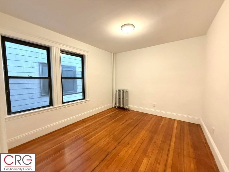 24 University Road, Unit 1 Brookline, MA 02446 - Photo 18 of 38 a view of an empty room with wooden floor and a window