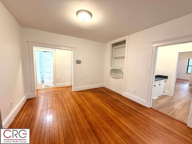 24 University Road, Unit 1 Brookline, MA 02446 - Photo 2 of 38 an empty room with wooden floor and windows
