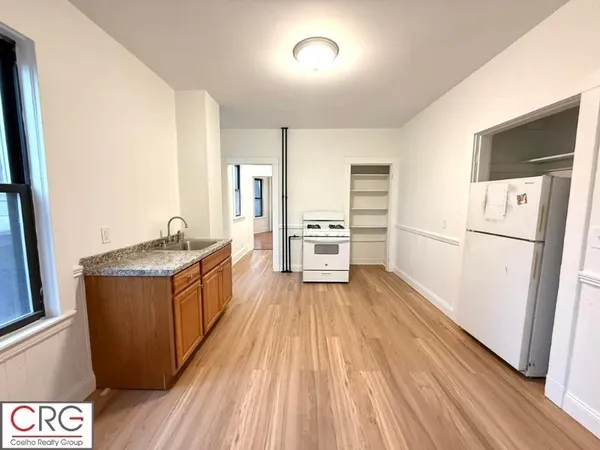 a kitchen with sink a refrigerator and wooden floor