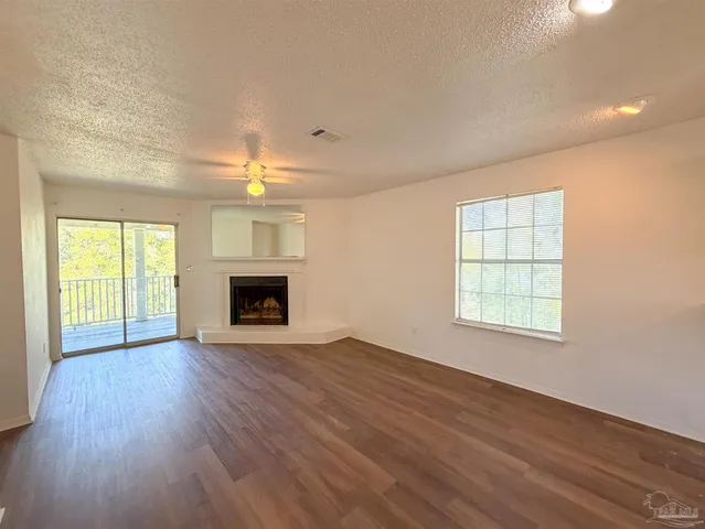 an empty room with wooden floor fireplace and windows