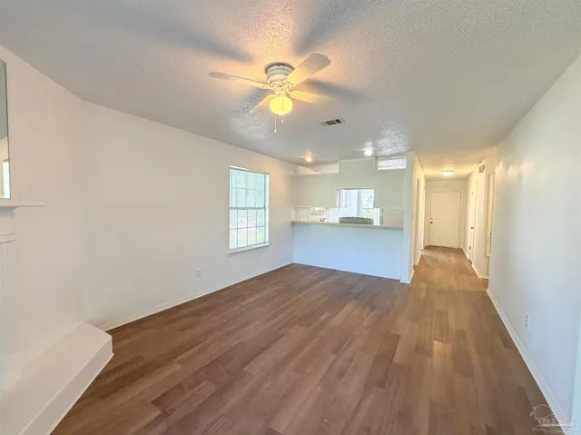 a view of an empty room with window and wooden floor