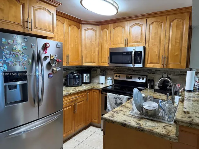 a kitchen with stainless steel appliances granite countertop a refrigerator sink and stove