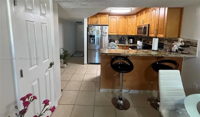 a kitchen with granite countertop a sink a counter appliances cabinets and a potted plant