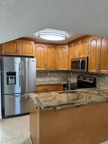 a kitchen with stainless steel appliances granite countertop a refrigerator a stove and a sink