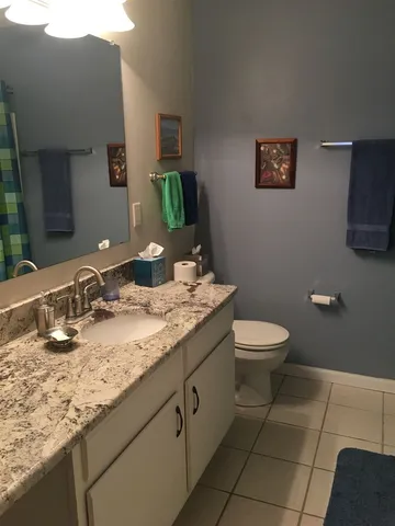 a bathroom with a granite countertop toilet sink and mirror