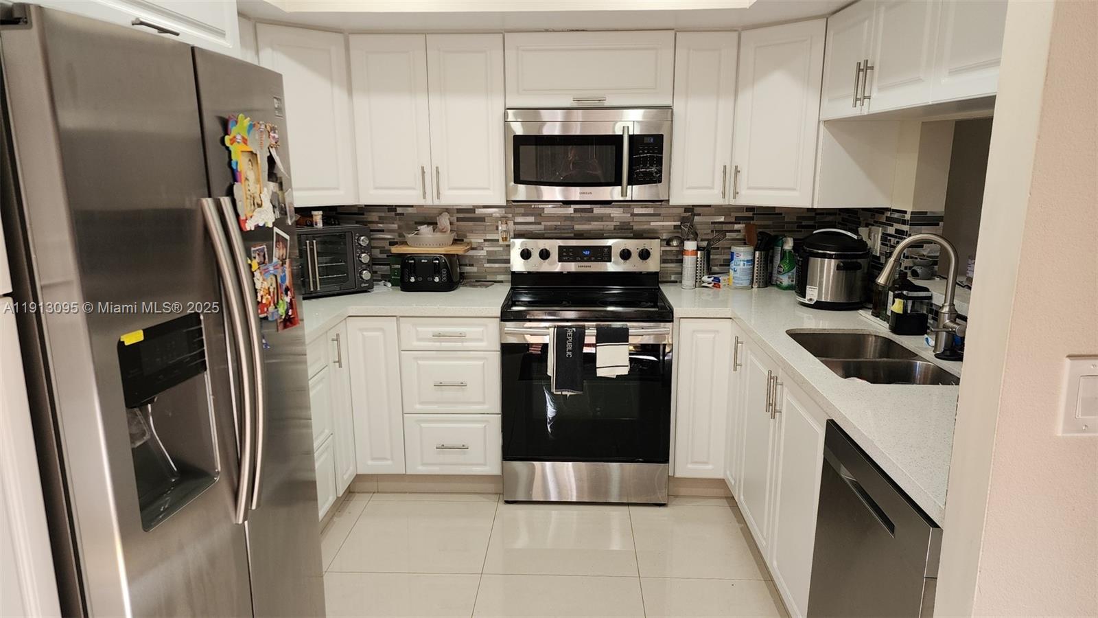 5975 Southwest 137th Avenue, Unit 803 Miami, FL 33183 - Photo 12 of 31 a kitchen with stainless steel appliances a refrigerator stove and sink