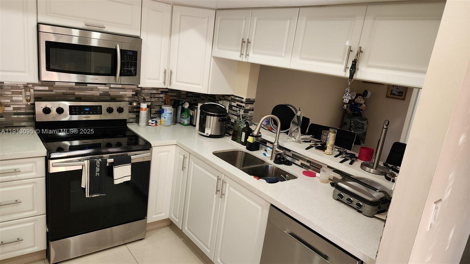 5975 Southwest 137th Avenue, Unit 803 Miami, FL 33183 - Photo 14 of 31 a kitchen with a sink a stove and microwave