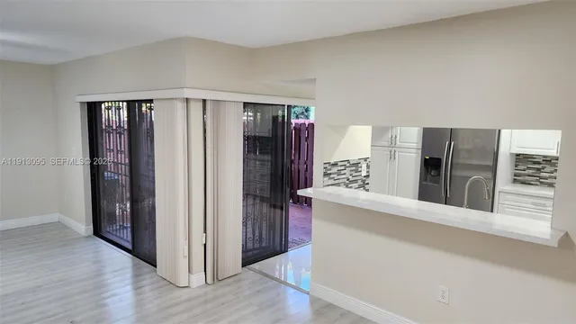 a view of a kitchen with refrigerator and wooden floor