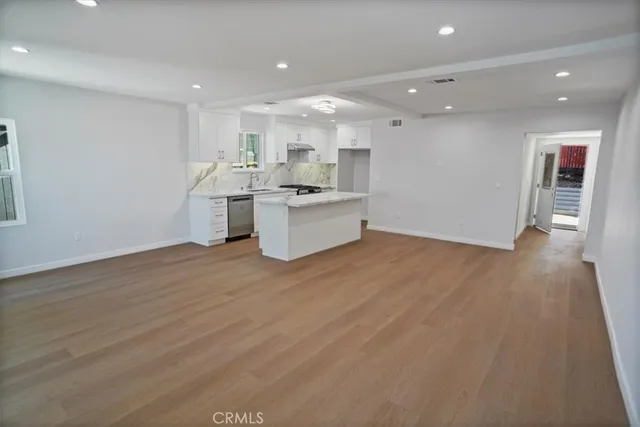 a large kitchen with a large counter top a sink stainless steel appliances and cabinets