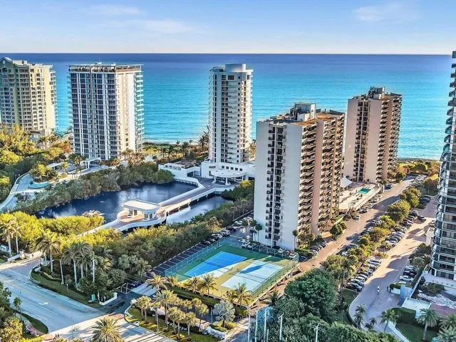 a view of an empty room with floor to ceiling window and kitchen