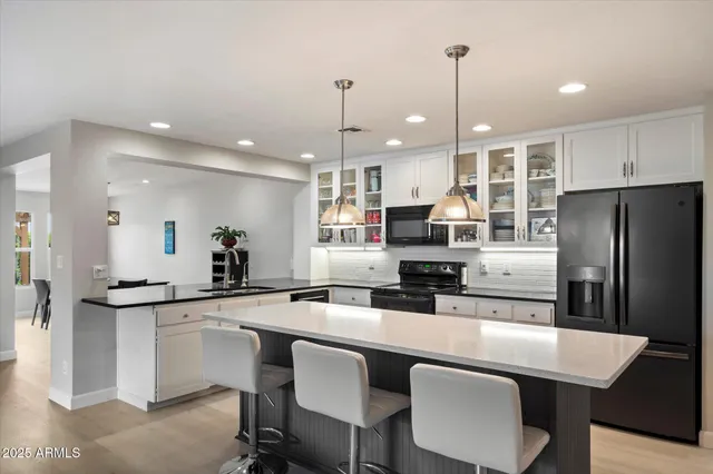 a kitchen with stainless steel appliances a sink a stove a refrigerator with a dining table and chairs