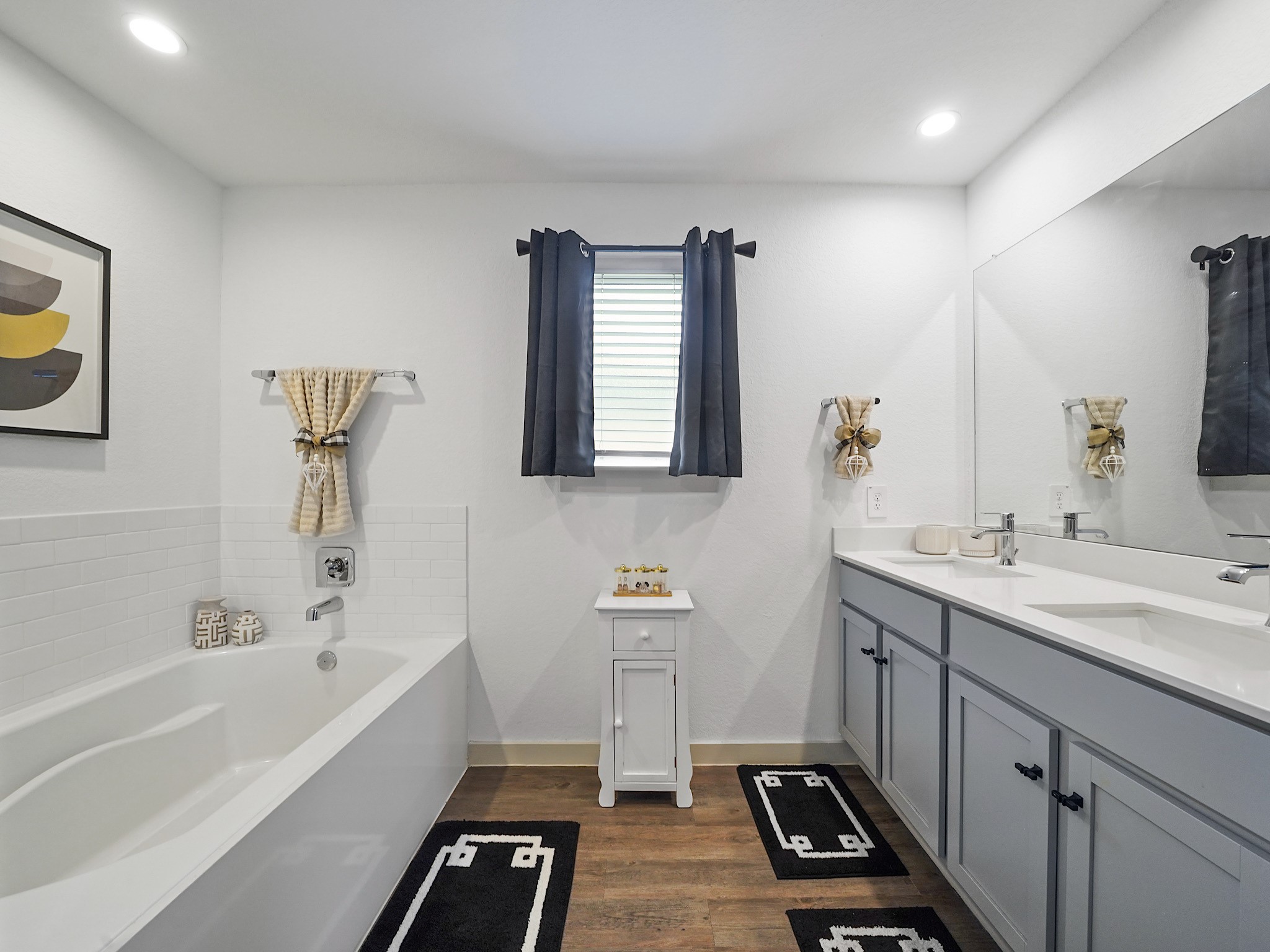 7823 Cattlewood Pass Rosharon, TX 77583 - Photo 14 of 17 The primary bathroom has both a sitting tub and a stand up shower, elegant white cabinetry with a large mirror, and stylish flooring.