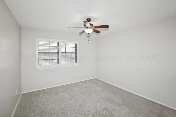 an empty room with a window and a ceiling fan