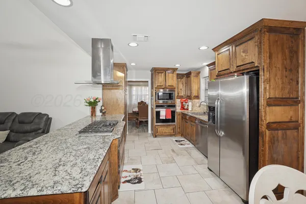 a kitchen with stainless steel appliances granite countertop a refrigerator a stove and a sink