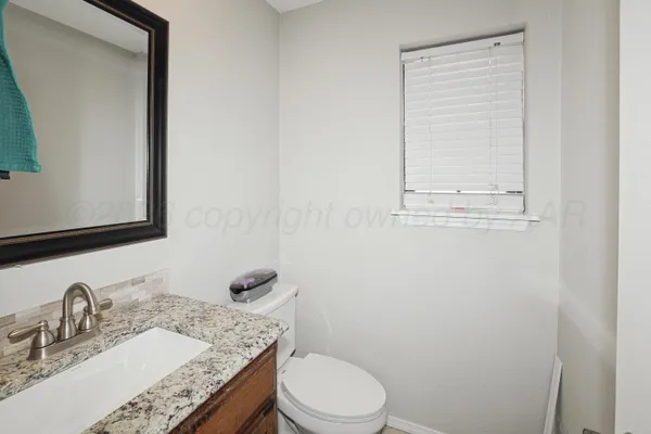 a bathroom with a granite countertop toilet a sink and mirror